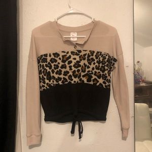 A fancy shirt that is black, beige, and cheetah print.